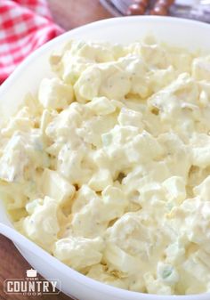 a white bowl filled with potato salad on top of a wooden table