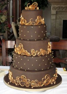 a three tiered chocolate cake with gold decorations