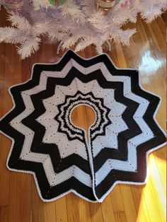 a black and white crocheted rug sitting on top of a wooden floor