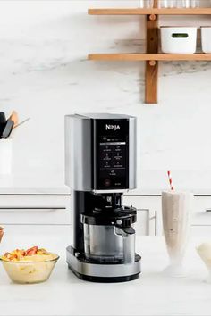 a coffee maker sitting on top of a kitchen counter next to bowls and cups filled with food