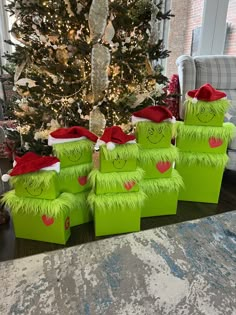 green boxes with faces on them are stacked in front of a christmas tree and other decorations