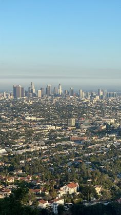 an aerial view of a city with tall buildings and lots of trees in the foreground