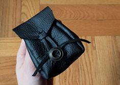 a hand holding a black leather case with a ring on the inside and an opening in the outside