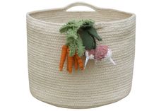 a basket with some carrots and other things in it on top of a white surface