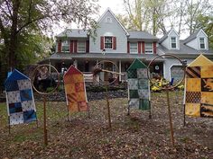 several pieces of art are displayed in front of a house with trees and leaves on the ground