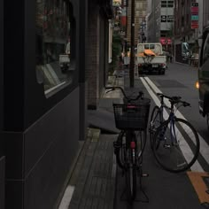 a bike parked on the side of a street next to a building with cars driving down it