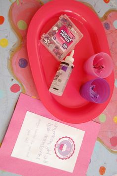 a pink heart shaped tray with two items on it and a note attached to the lid