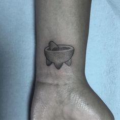 a black and white photo of a small bowl tattoo on the left inner wrist area