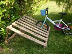 a small child's bike sitting on top of a wooden slatted bench