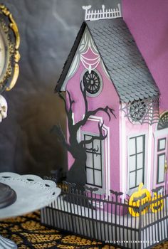 a paper house with a clock on the table next to it and other decorations around it