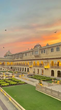 a large building with lots of windows and plants in front of it at sunset or dawn