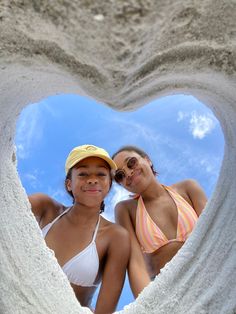 two girls are standing in the shape of a heart