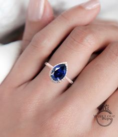 a woman's hand with a diamond and blue sapphire ring on her left hand