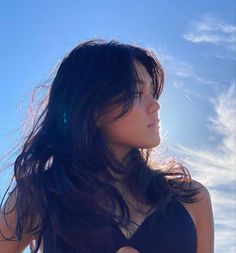 a woman with long black hair standing in the sun