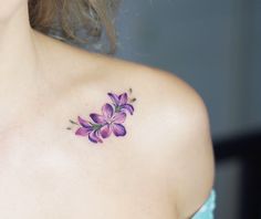 a woman's shoulder with purple flowers on the left side of her arm and chest