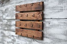 three wooden pegs mounted to the side of a wall with hooks on each one