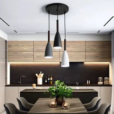 a modern kitchen with wooden cabinets and black counter tops, along with hanging lights above the dining room table