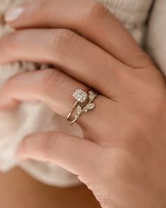 a woman's hand wearing a gold ring with three leaves on it and a diamond band