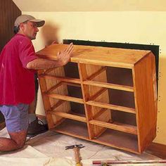 a man standing next to a wooden bookcase with shelves on it's sides