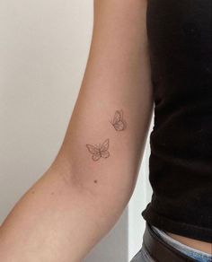 a woman's arm with two small butterflies on the left side of her arm