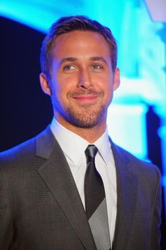 a man in a suit and tie smiling at the camera with blue lights behind him