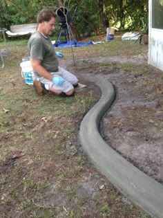 a man sitting on the ground next to a garden hose and water bottle in his hand