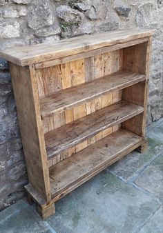 an old wooden bookcase sitting next to a stone wall