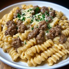 pasta with meatballs and gravy on a plate sitting on a wooden table