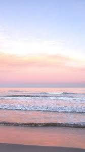 two people walking on the beach at sunset