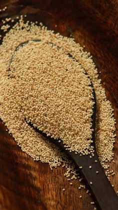 a spoon full of sesame seeds on top of a wooden table