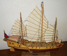 a model sailboat on a wooden stand with white walls in the background and wood flooring