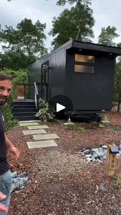 a man standing in front of a tiny house