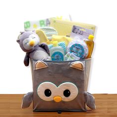 a stuffed animal sitting inside of a bag filled with baby items on top of a wooden table