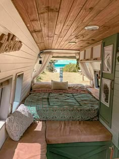 the inside of a camper that has a bed and pillows on top of it