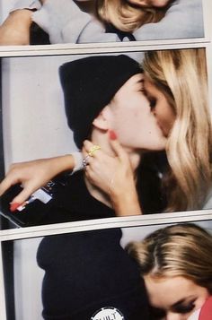 two women kissing each other while wearing beanies and holding onto one another's finger