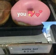 donuts with pink frosting and hearts on them in a display case at a store