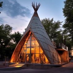 a large triangular shaped building with glass windows and people standing in the doorway at night