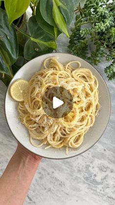 someone holding a plate of spaghetti with lemon slices