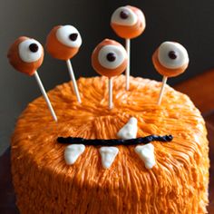 an orange cake with eyes and sticks sticking out of it