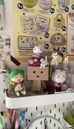 some toys are sitting on a shelf in front of a wall with pictures and other items