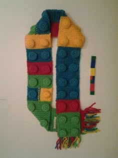 a knitted scarf with legos on it next to a crochet pencil