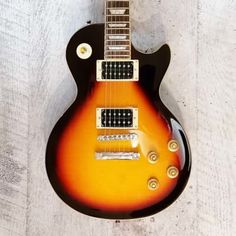 an electric guitar sitting on top of a wooden floor next to a white board wall