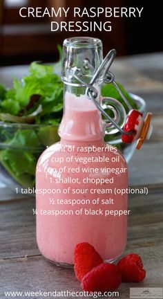 a bottle filled with raspberry dressing next to a bowl of lettuce