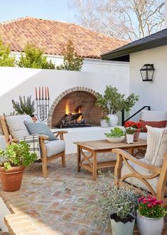 an outdoor living area with chairs, tables and fire place in the middle of it