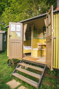 a small yellow shed sitting on top of a lush green field