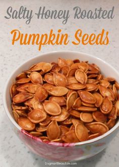 a bowl filled with roasted pumpkin seeds on top of a counter next to the words, salty honey roasted pumpkin seeds