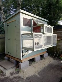 a chicken coop built into the side of a backyard with no roof and windows on it