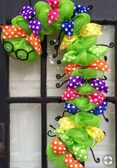 a green wreath with polka dot bows and glasses hanging on a window sill in front of a black door