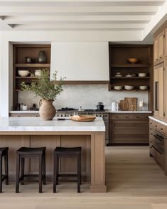 a large kitchen with wooden cabinets and counter tops, along with two stools in front of the island