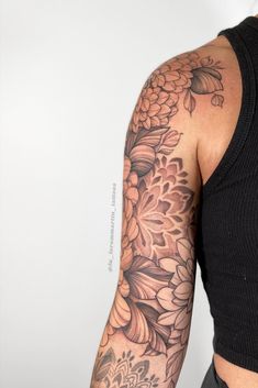 a woman's arm with flowers and leaves tattooed on the back of her arm